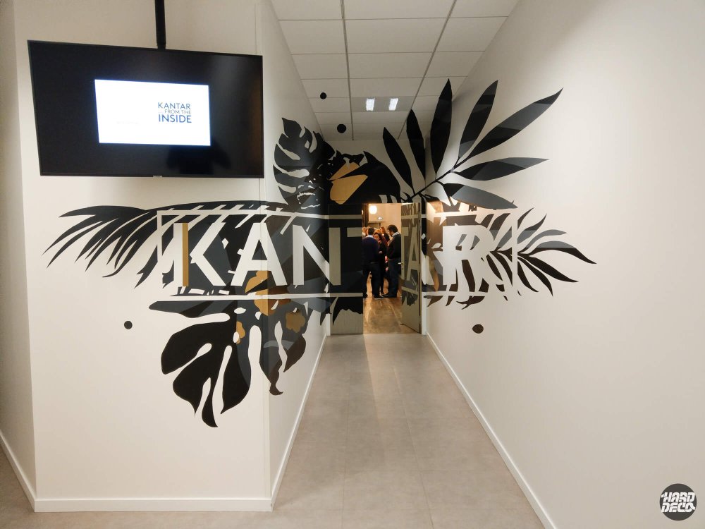 Vue couloir bureaux Kantar Paris avec anamorphose végétale noir et or et lettrage marque intégré