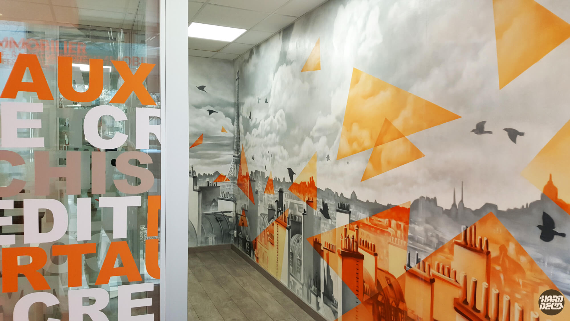 Fresque murale panoramique Paris couloir agence Meilleurtaux, toits et Tour Eiffel gris avec triangles orange