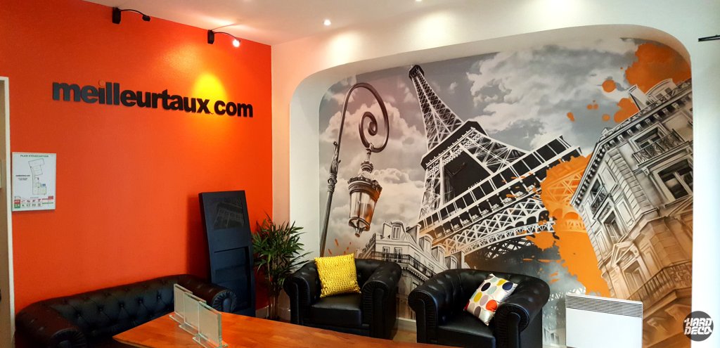 Salle d'attente agence Meilleurtaux Paris 17e avec fresque Tour Eiffel aérosol orange et gris, canapés cuir
