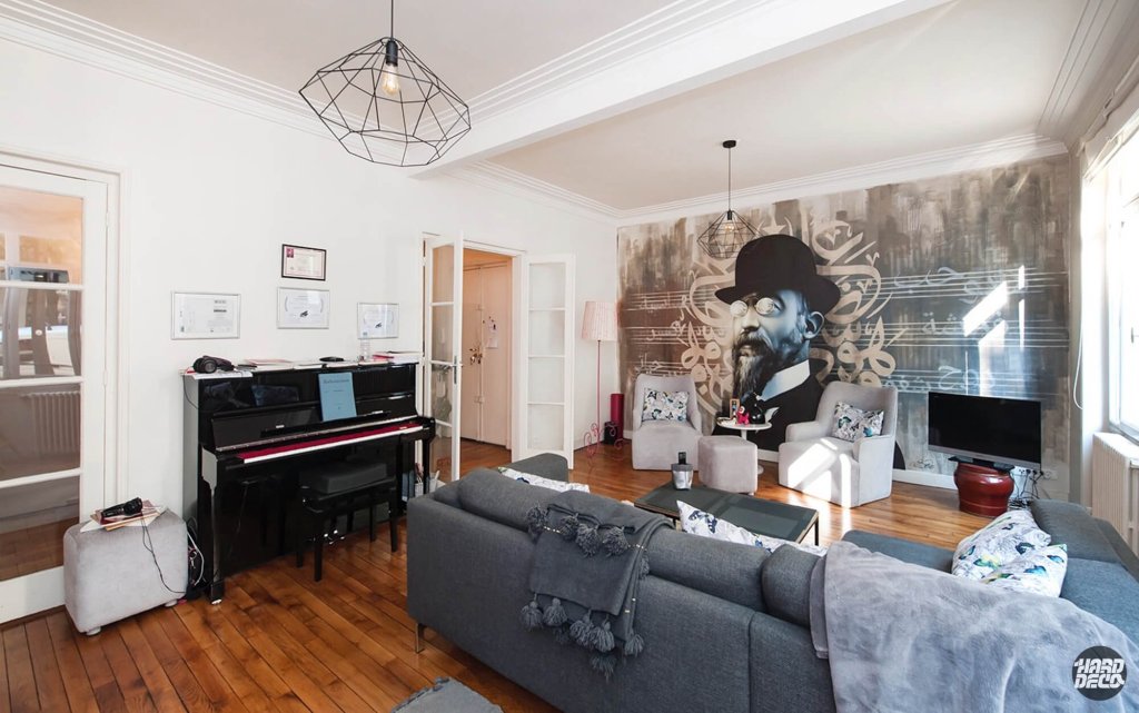 Fresque murale portrait Erik Satie à l'aérosol dans un salon parisien avec piano et calligraphie arabe