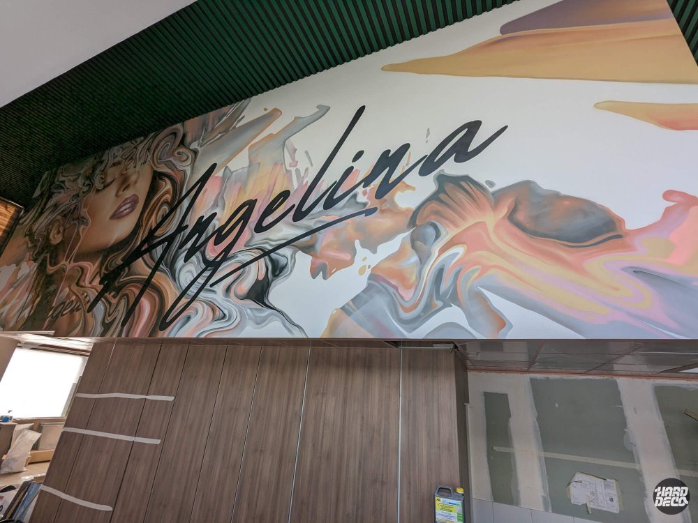 Fresque murale restaurant L'Angélina Paris, portrait féminin abstrait et lettrage cursif noir sur fond clair