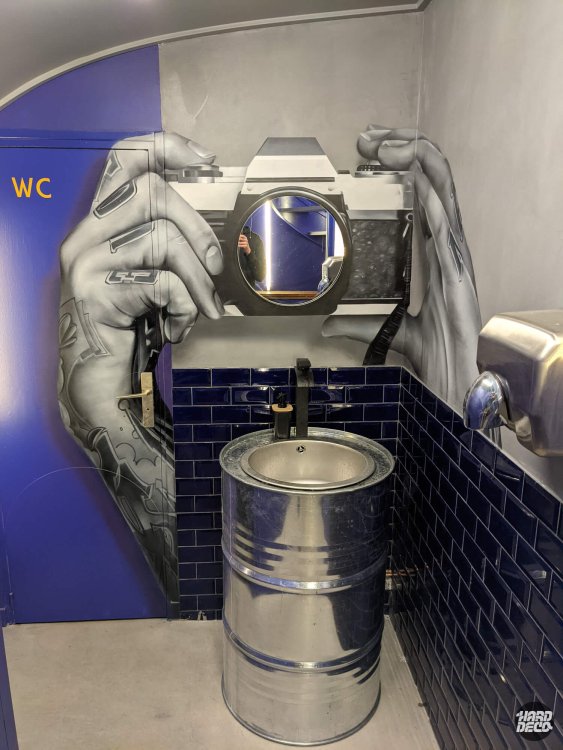 Fresque trompe-l'œil hyperréaliste appareil photo avec miroir en objectif, WC restaurant Paris
