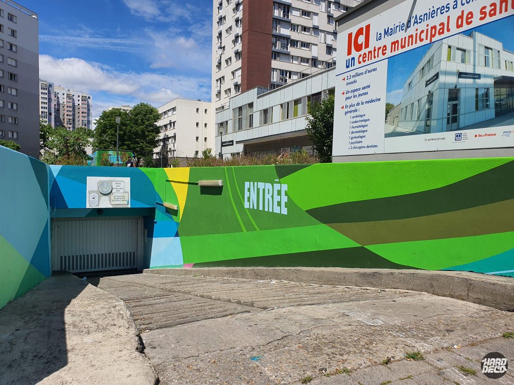 Mur entrée parking collectif fresque verte géométrique avec inscription ENTRÉE en lettres blanches
