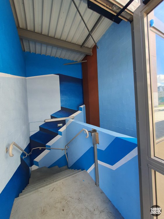 Cage d'escalier extérieure peinte en bleu cobalt et blanc avec motifs géométriques diagonaux