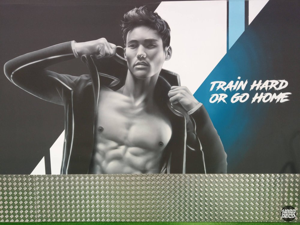 Portrait athlétique homme torse nu en gris, slogan Train Hard Or Go Home, fresque aérosol Fitness Park Pierrefitte