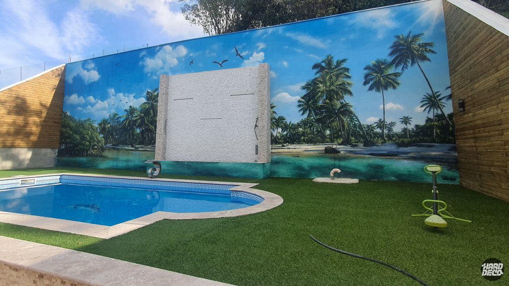 Fresque murale hyperréaliste plage tropicale et lagon turquoise sur mur de piscine privée, vue d'ensemble