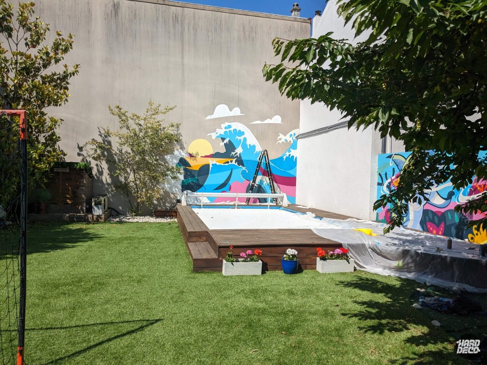 Vue d'ensemble du jardin avec piscine et fresque vague Hokusai en cours de réalisation sur mur en béton