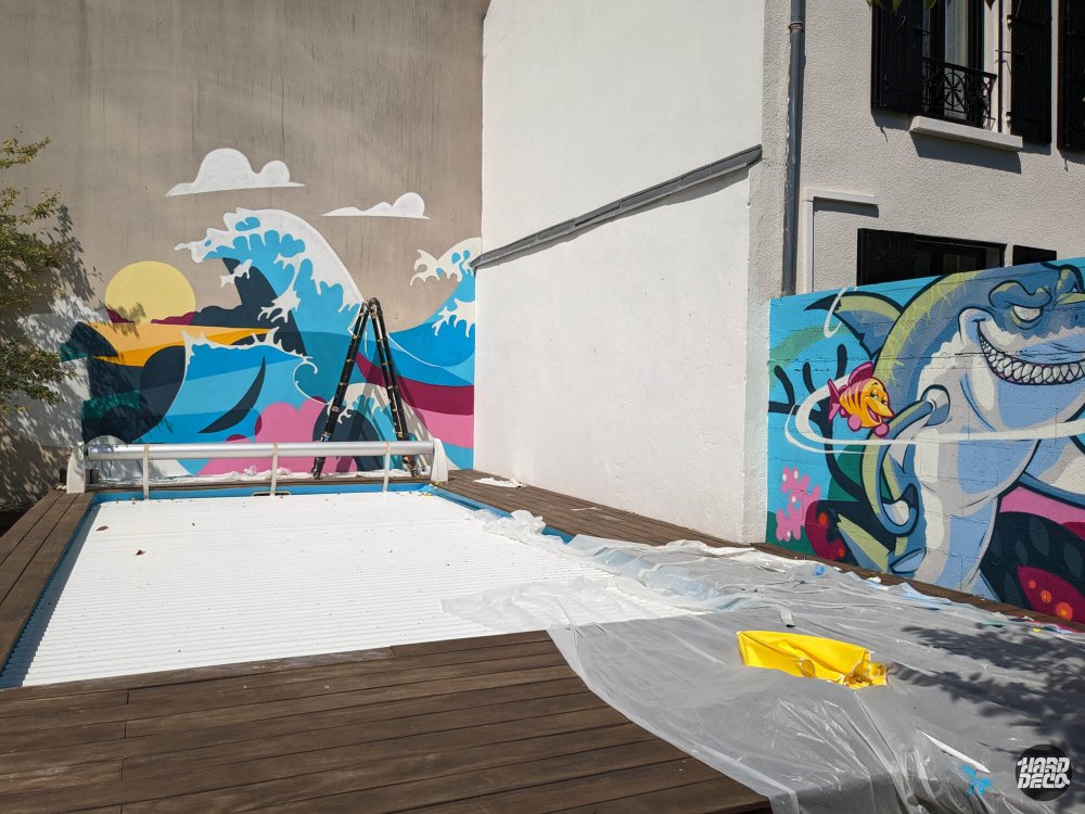 Piscine en bois encadrée par la fresque vague à gauche et le requin à droite, vue latérale