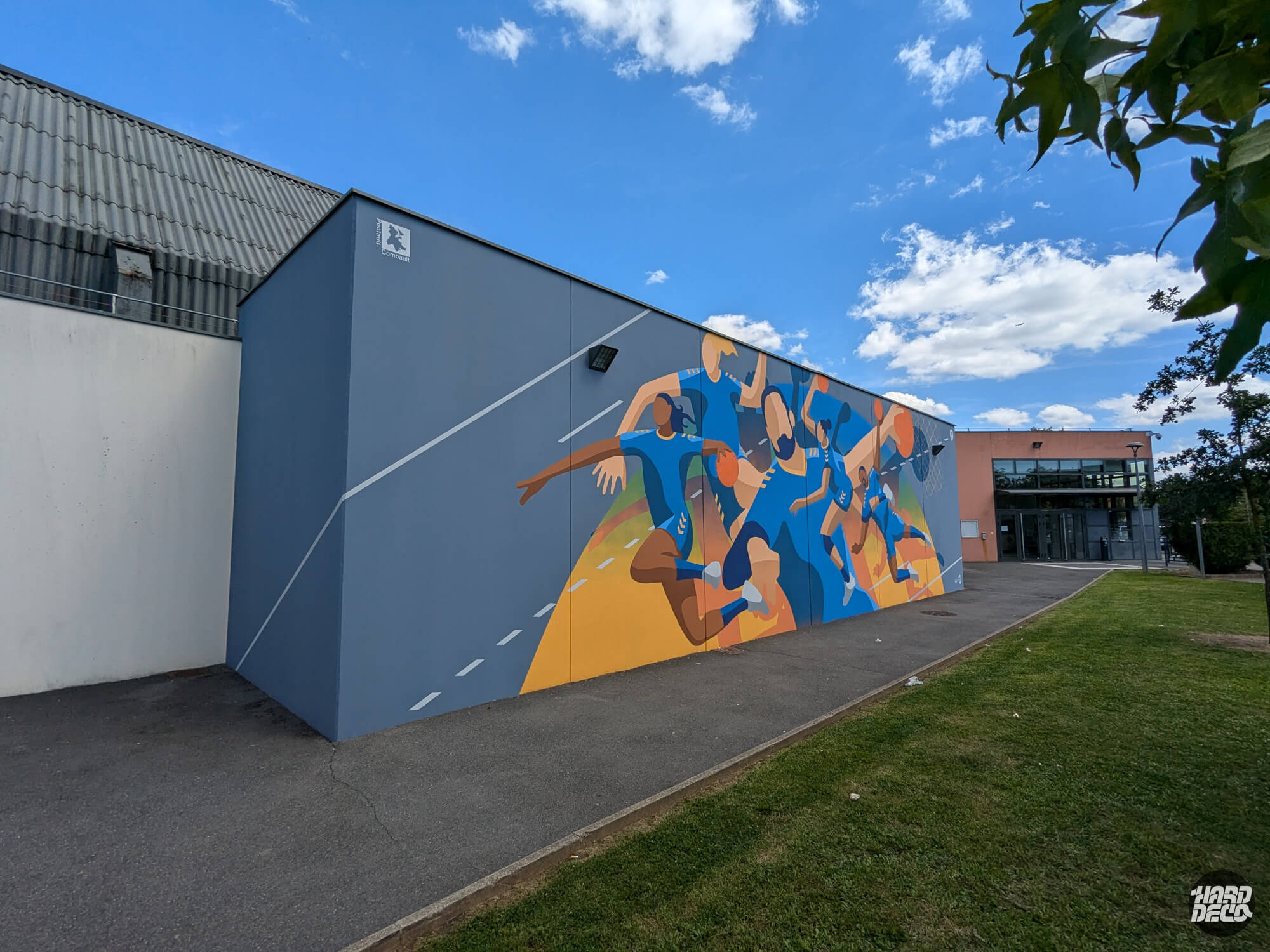 Fresque murale handball sur façade de gymnase à Pontault-Combault, vue d'ensemble depuis l'angle du bâtiment