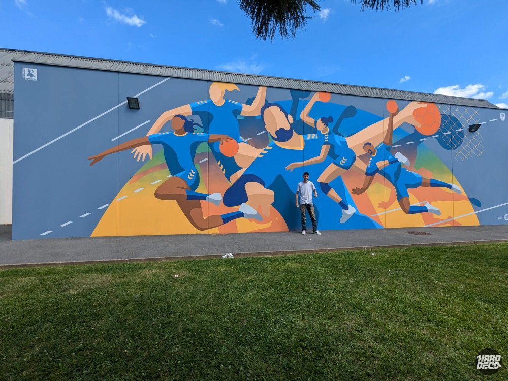 Fresque handball gymnase Roger Boisramé vue de face avec artiste Shero devant le mur peint, Pontault-Combault