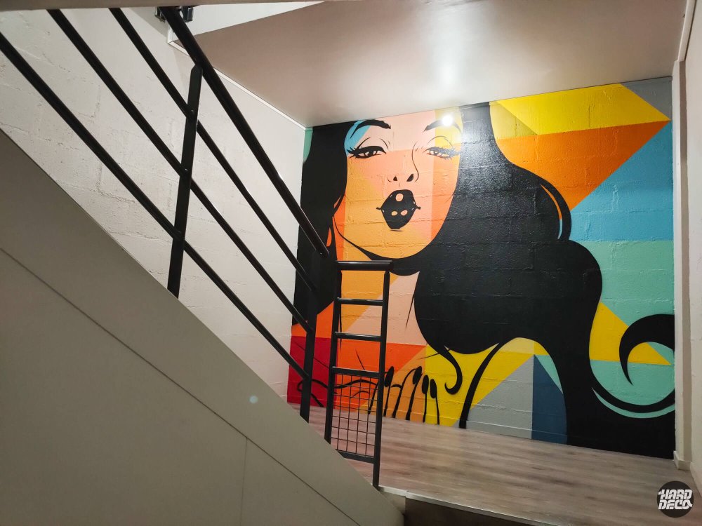 Fresque pop art portrait femme cheveux noirs fond géométrique orange jaune turquoise dans escalier bureaux
