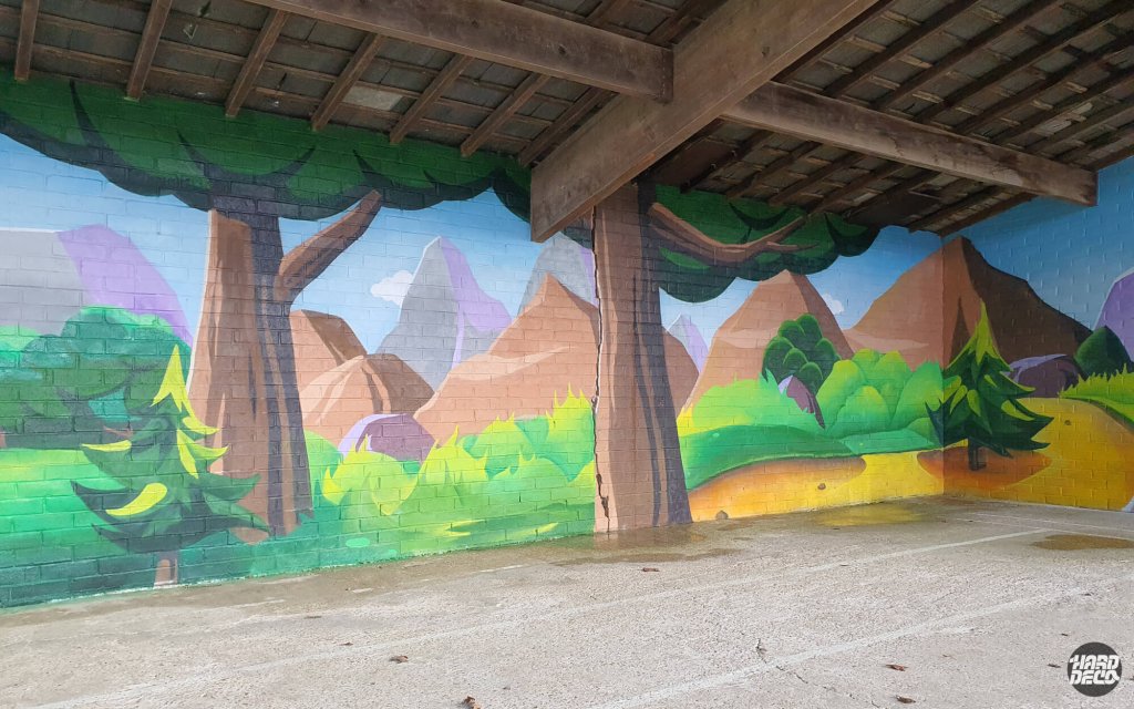 Fresque murale préau école Torcy, paysage montagne stylisé avec grands arbres et sommets, vue d'angle intérieur