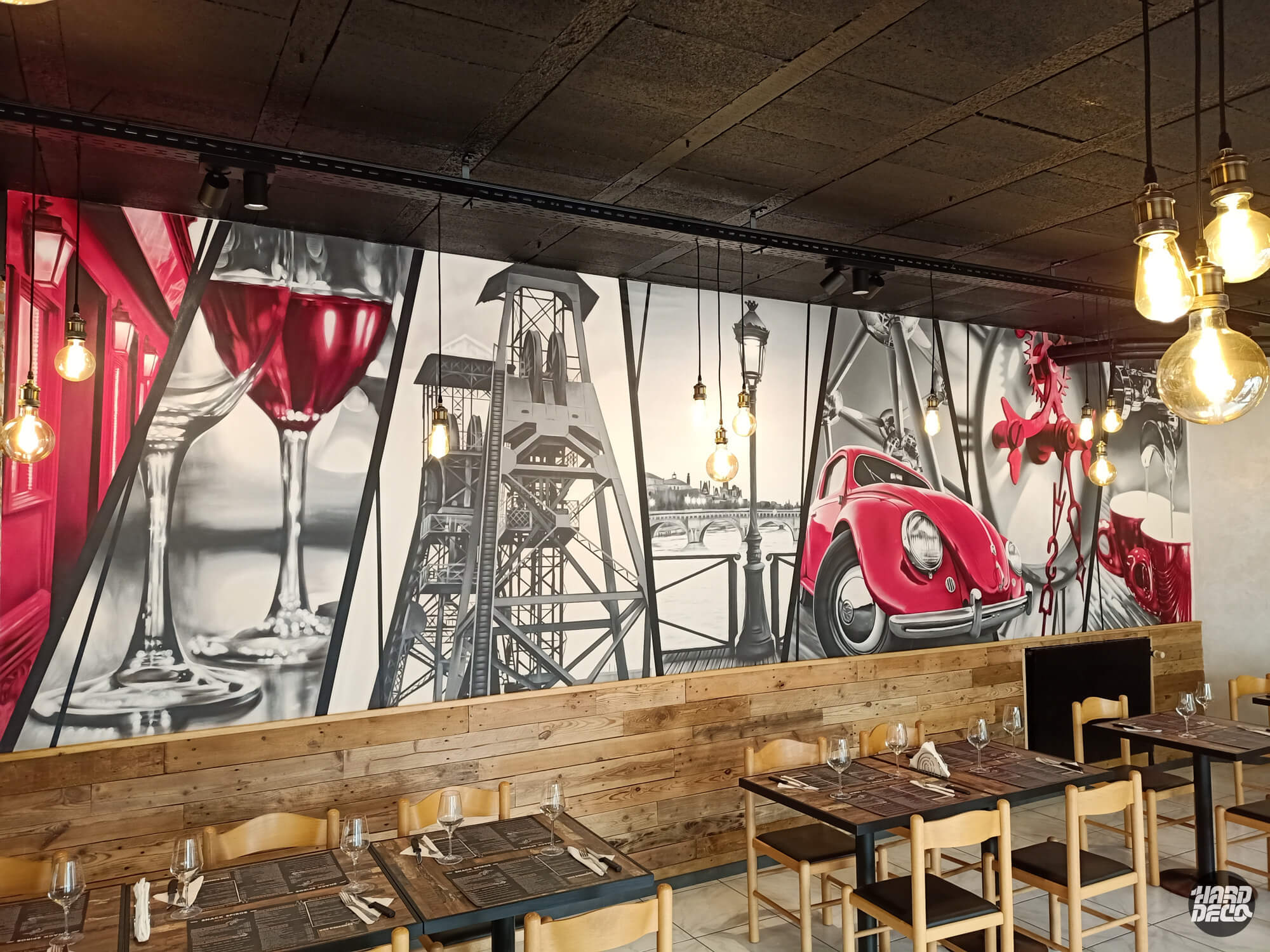 Détail fresque aérosol restaurant : verres de vin rouges, tour industrielle et Coccinelle cerise sur fond noir et blanc