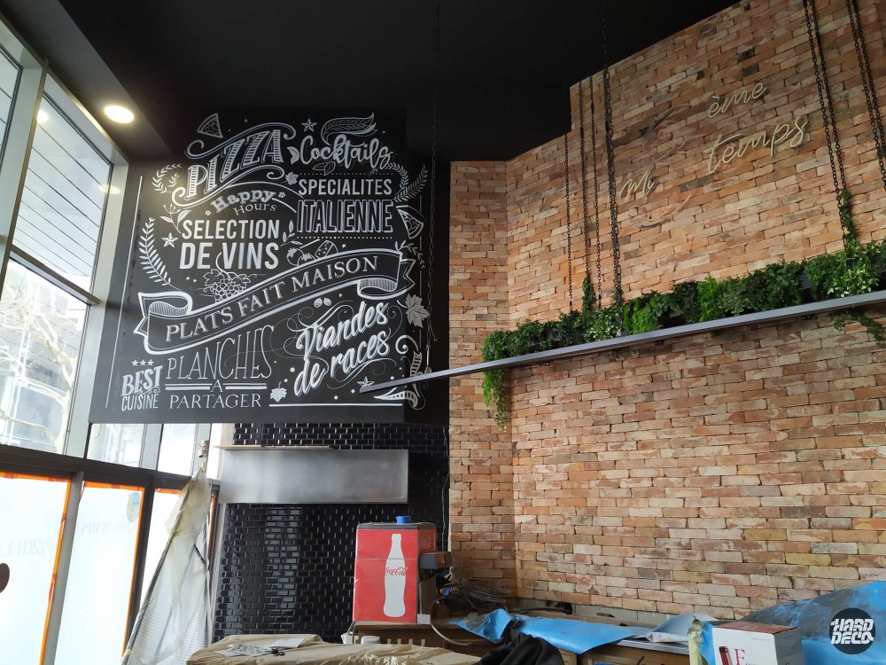 Lettrage typographique chalk art sur mur noir au-dessus du bar, restaurant 3ème Mi-Temps Saint-Denis