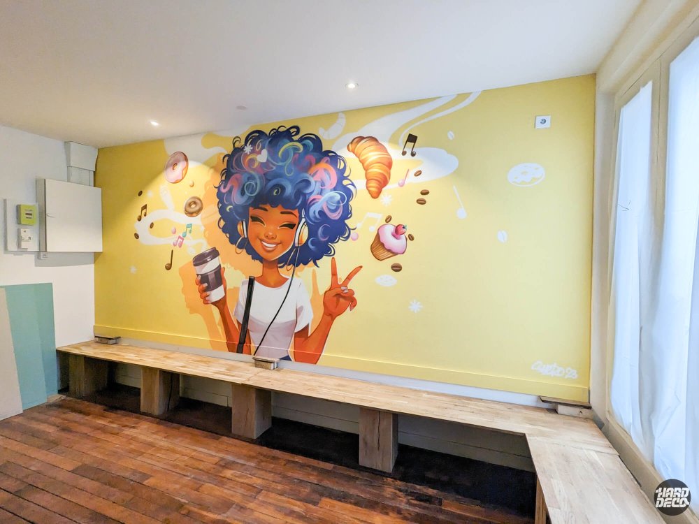 Vue d'ensemble fresque aérosol Coffee Kat Saint-Maur, personnage manga fond jaune, banquettes bois, salle de café