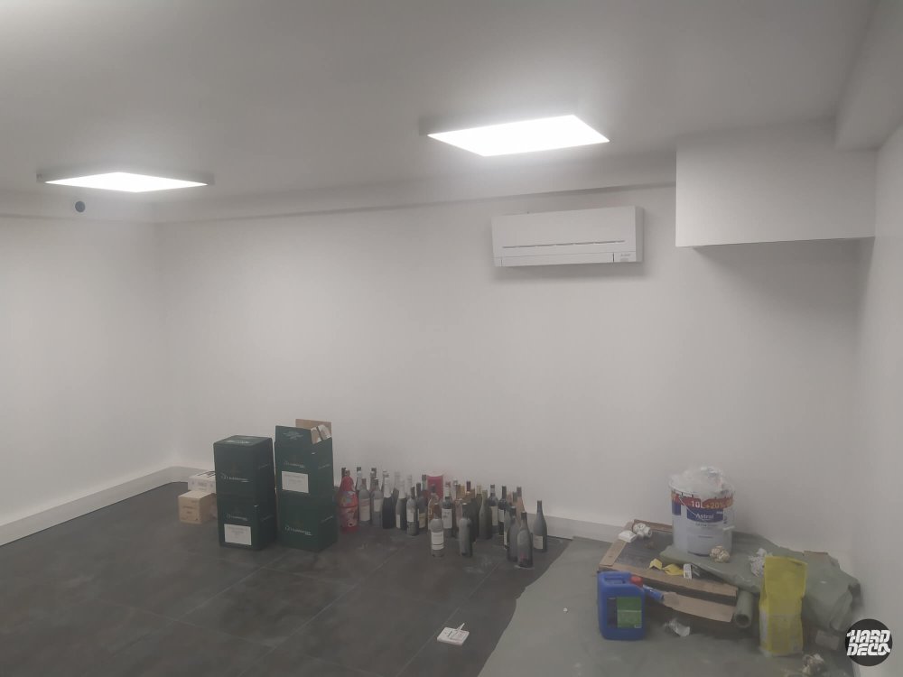 Salle gaming avant intervention, murs blancs vides avec climatiseur et carrelage sombre