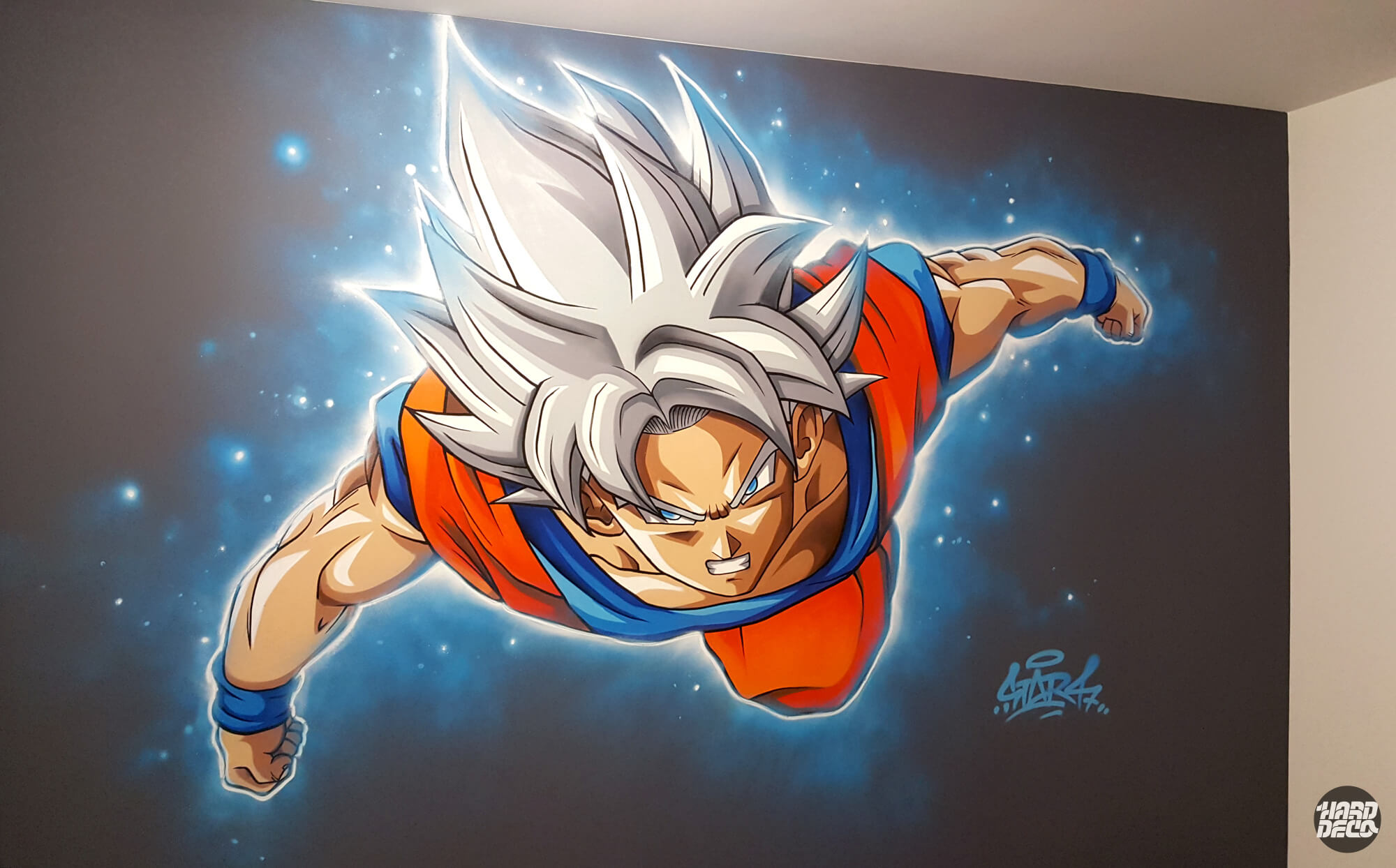 Fresque murale Sangoku Ultra Instinct Dragon Ball, aérosol sur mur gris, aura bleue et gi orange