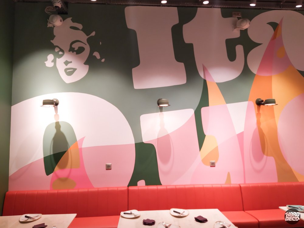 Portrait féminin pop et typographie Italian Queen Serris, aplats vert gris rose poudré mur restaurant