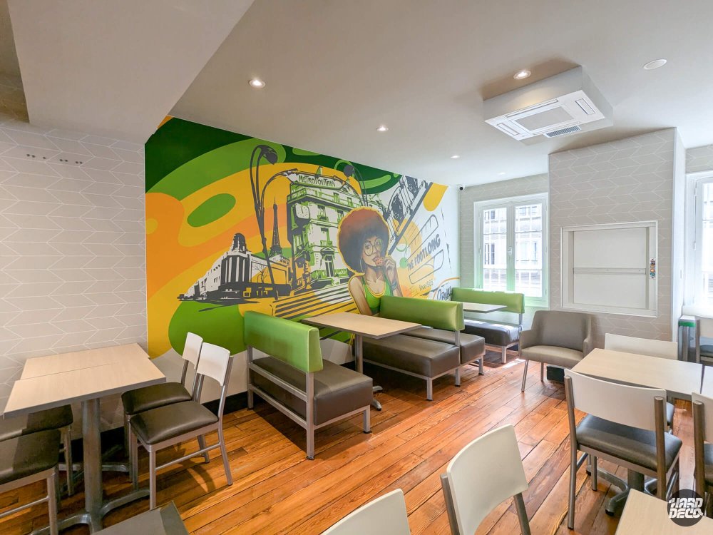 Vue d'ensemble salle restaurant Subway Paris 2e avec fresque murale street art sur toile en fond de salle
