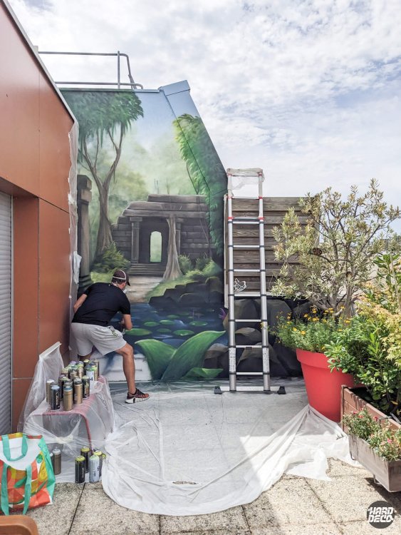 Vue en cours de réalisation de la fresque jungle avec temple et bassin de nénuphars à l'aérosol