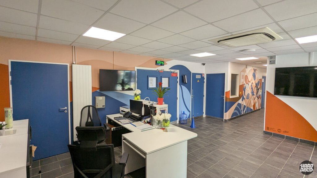 Vue d'ensemble de l'accueil du comité de tennis, décor mural sur plusieurs murs orange bleu saumon