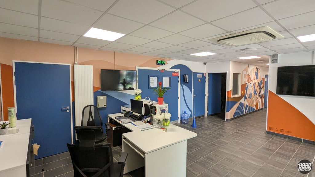 Accueil du comité de tennis avec décor mural sport, couloir illustré de joueurs de tennis stylisés
