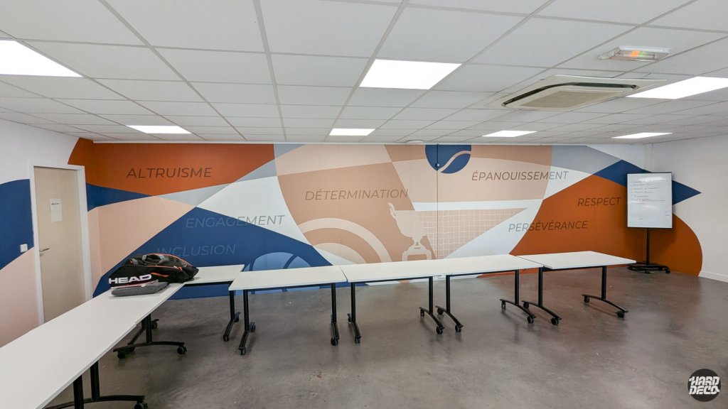 Salle de réunion club de tennis, mur peint avec valeurs sportives et formes géométriques colorées