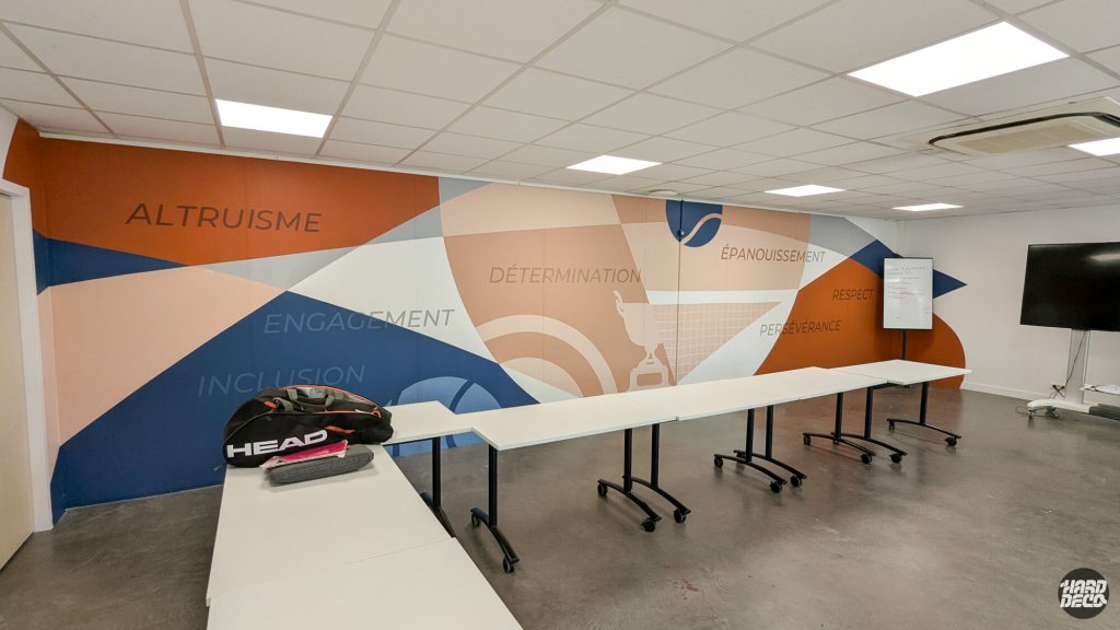 Vue complète du mur de la salle de réunion, composition géométrique et mots altruisme engagement inclusion