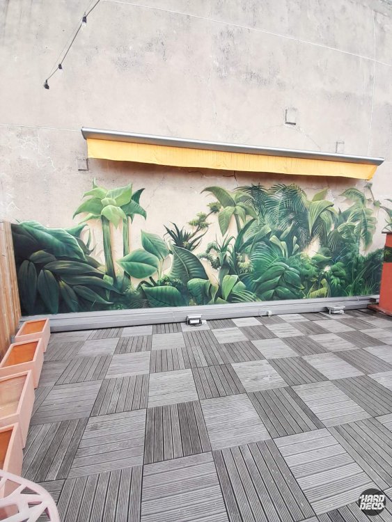 Fresque aérosol nature jungle sur mur extérieur terrasse, palmiers et feuillage vert profond