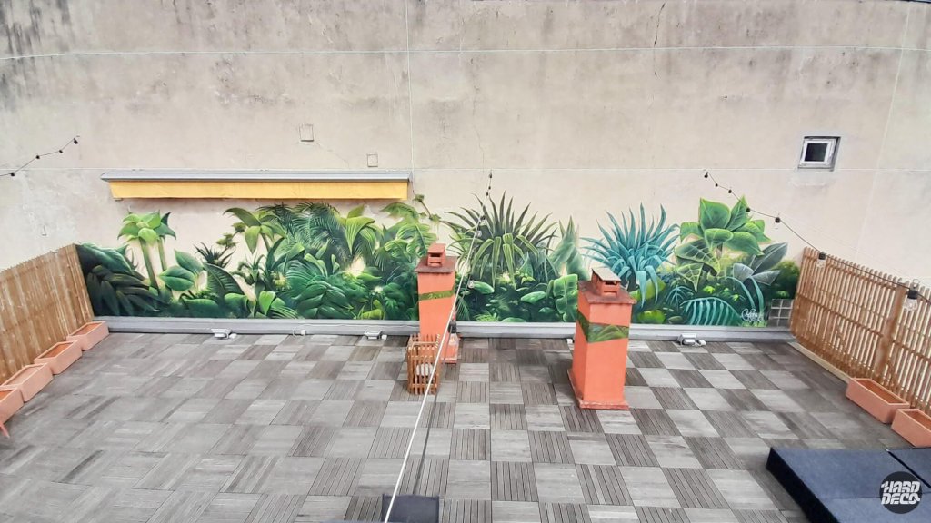 Vue d'ensemble fresque végétale tropicale sur deux murs de terrasse privée, palmiers et bananiers