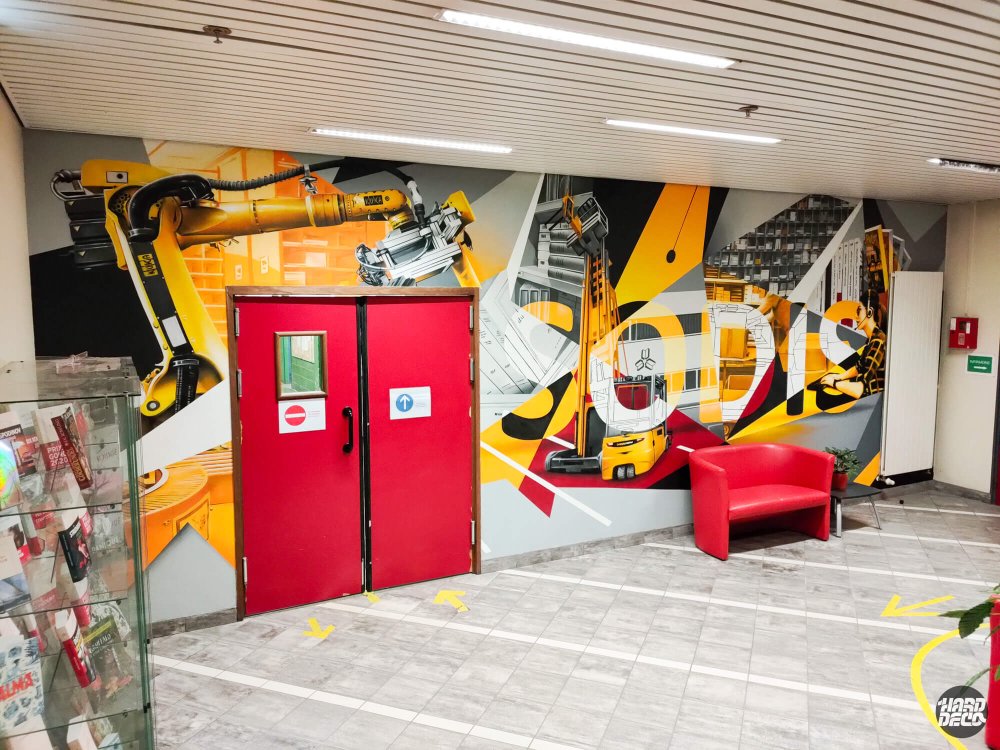 Vue d'ensemble fresque Sodis depuis l'entrée du hall, bras robotisé et portes industrielles rouges intégrées