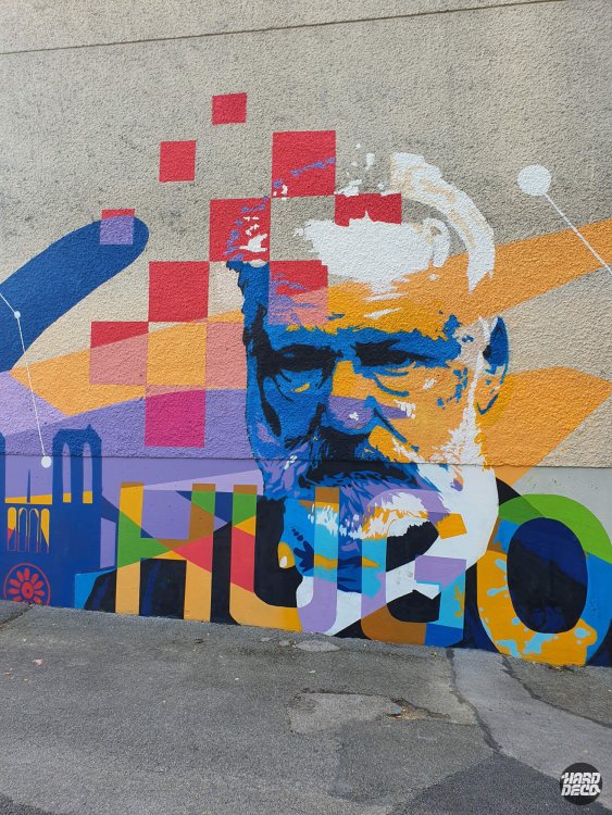 Portrait mural de Victor Hugo en bleu et orange avec typographie multicolore et motifs géométriques, école à Torcy