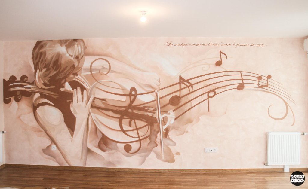 Fresque murale aérosol représentant une violoncelliste entourée de notes de musique en teintes sépia sur fond beige