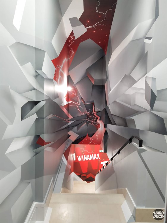 Cage d'escalier Winamax Paris, fresque immersive 3D blocs géométriques gris éclatés sur fond rouge
