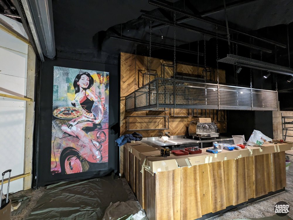 Installation toile pop art Miss Italia face au bar restaurant Paris, ambiance industrielle bois métal