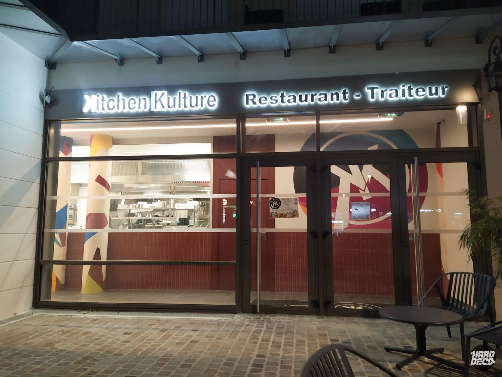 Façade du restaurant Kitchen Kulture Montévrain de nuit, décor peint visible derrière les vitres