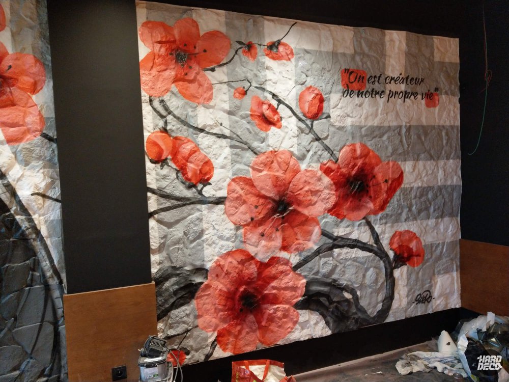 Détail toile florale restaurant Tuk Tuk Torcy : fleurs de cerisier rouges sur fond pierre avec citation calligraphiée