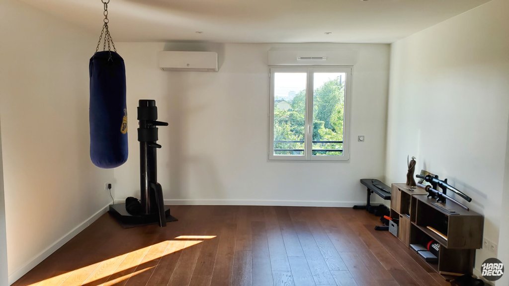 Salle de sport vide avant transformation en dojo japonais par trompe-l'œil, murs blancs et parquet