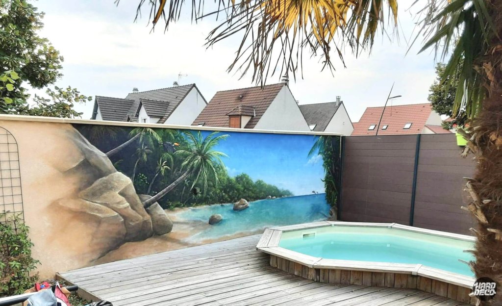 Fresque murale aérosol plage des Seychelles sur clôture extérieure, vue d'ensemble avec piscine et terrasse bois