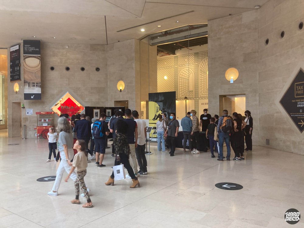 Public nombreux dans le hall du Louvre devant la toile Batman The World lors du live painting événementiel