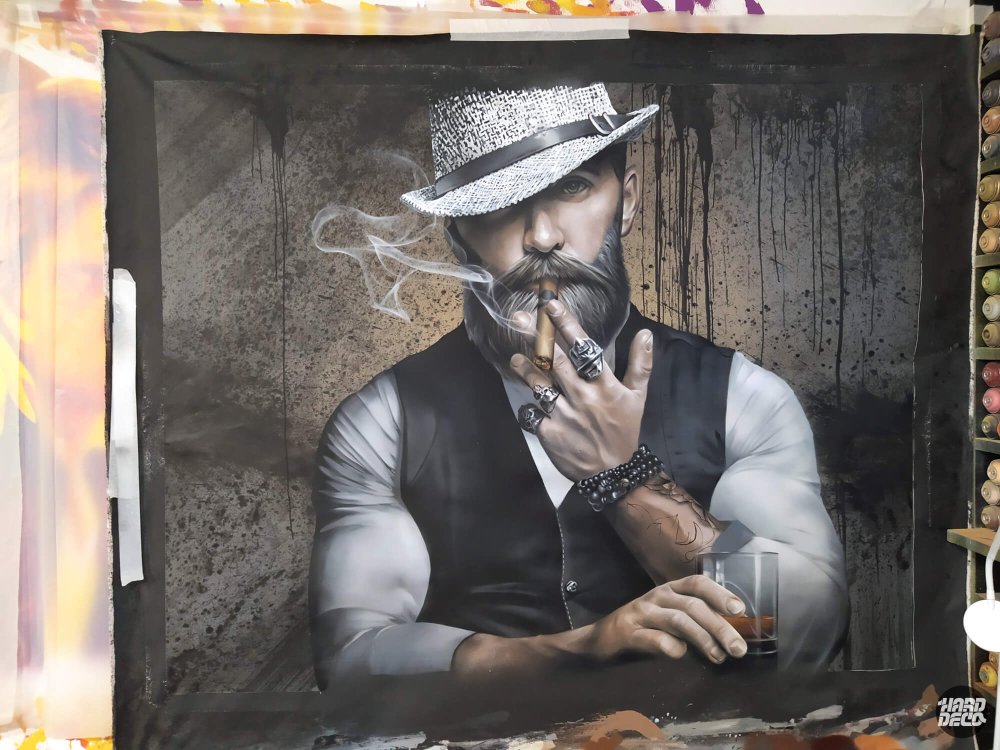 Portrait hipster aérosol sur toile en cours, homme barbu au cigare et chapeau blanc, fond texturé brun