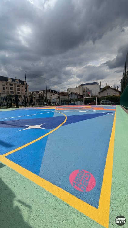 Détail sol terrain de basket Livry-Gargan, aplats bleus et jaune or avec logo Hard Déco intégré au sol