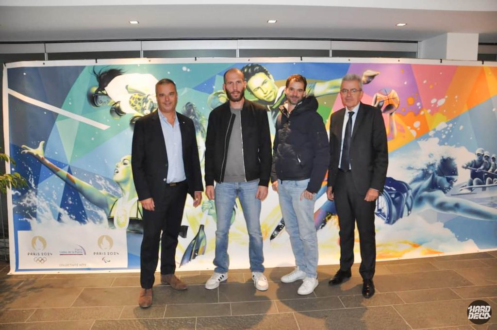 Quatre personnes devant la toile Paris 2024 lors de la soirée de présentation à Noisiel, logos JO visibles