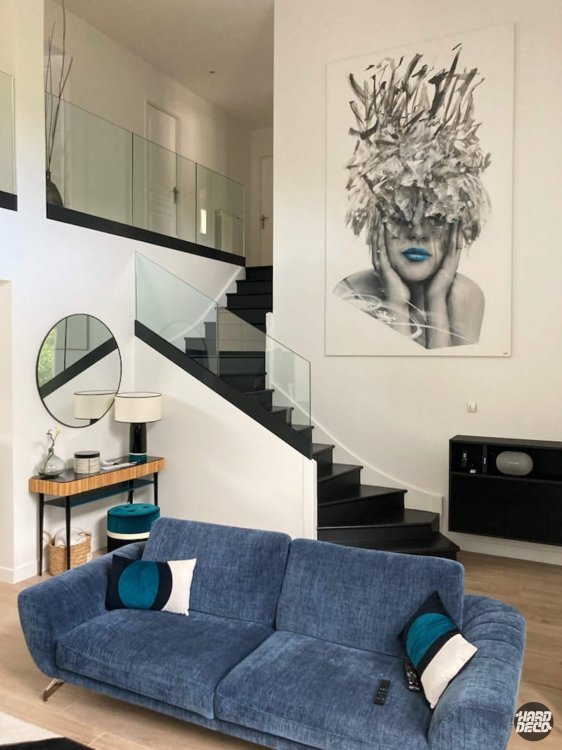 Toile portrait féminin noir blanc lèvres bleues dans salon double hauteur avec escalier et canapé bleu