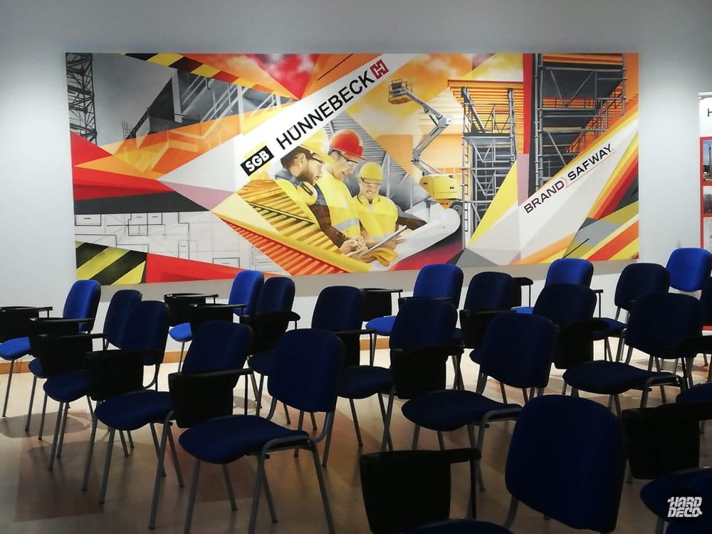 Fresque corporative Hunnebeck Brand Safway, salle avec chaises bleues, motifs industriels et logos intégrés