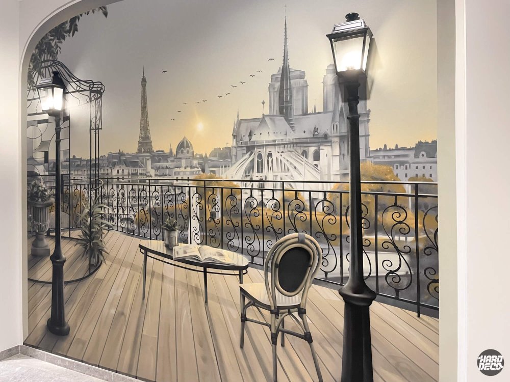 Fresque trompe-l'œil balcon haussmannien avec Tour Eiffel, garde-corps fer forgé et lampadaires, hall d'entreprise Rennes