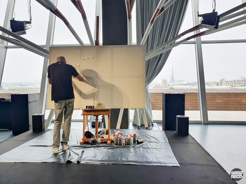 Artiste en train de peindre sur une grande toile dans un atelier avec vue sur la tour Eiffel