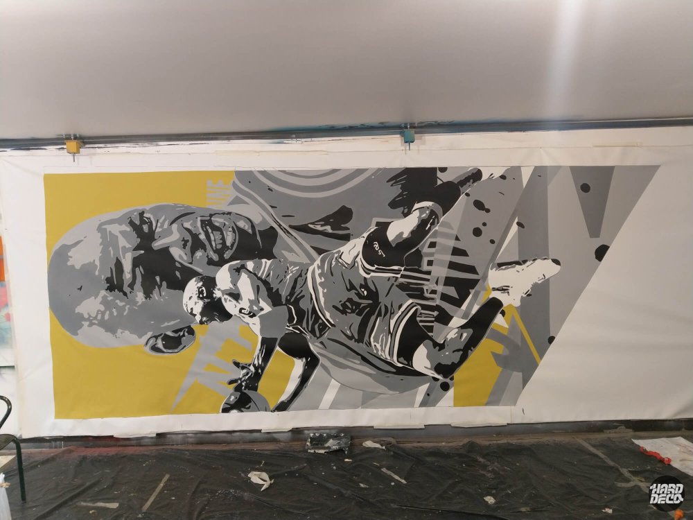 fresque murale en noir et blanc avec touches jaunes représentant un joueur de basket en action dans une salle de sport