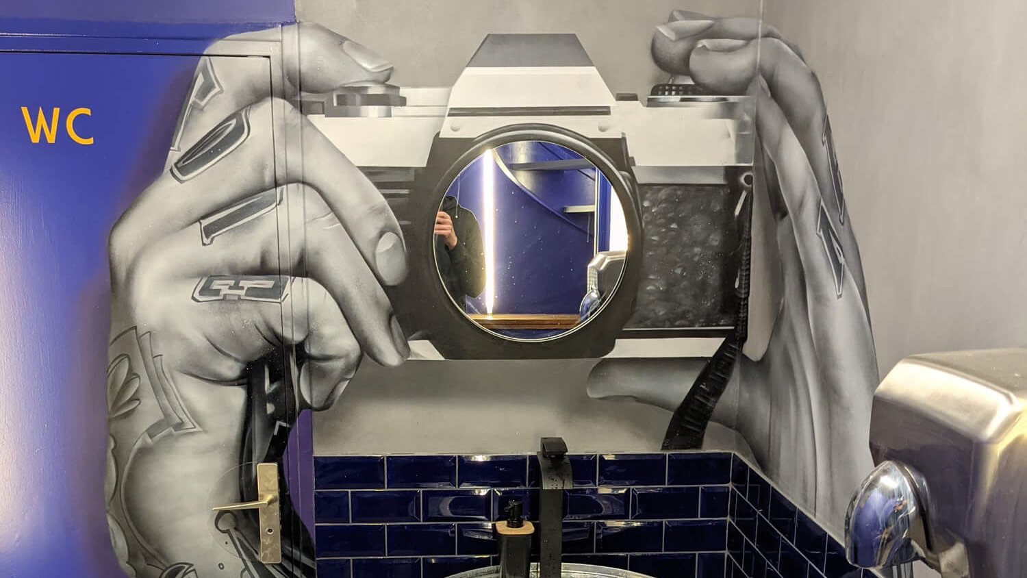 Fresque trompe-l'œil hyperréaliste appareil photo avec miroir en objectif, WC restaurant Paris